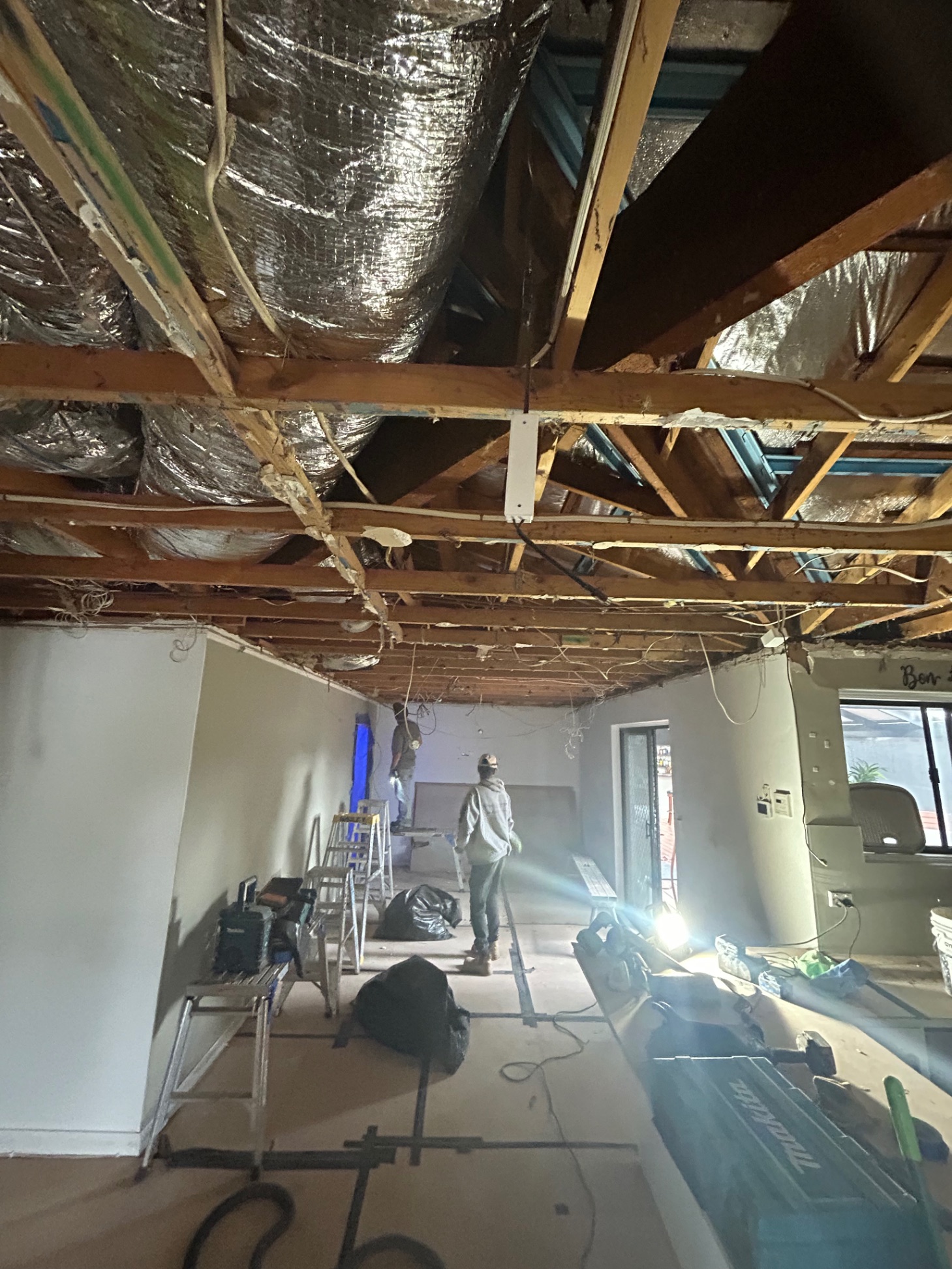 Tradesman on site with full ceiling stripped back exposing roof structure